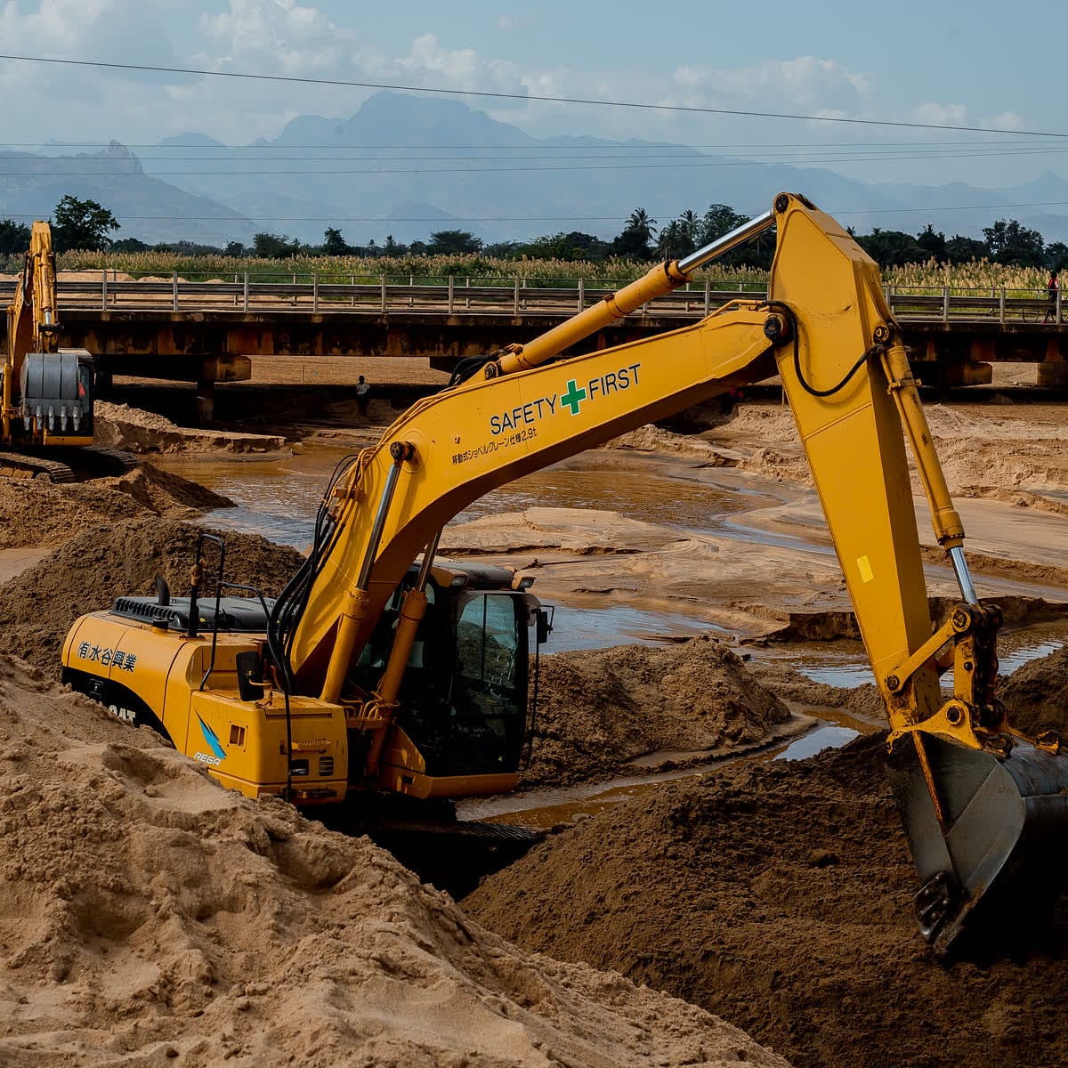 Ellyz excavator marked Safety First working beside a bridge crossing